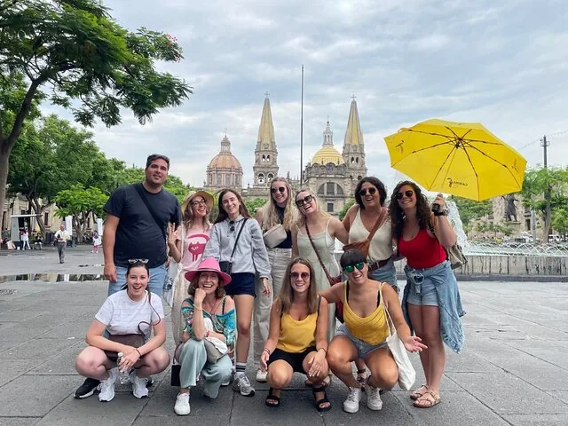Group of tourists posing in a plaza with Guadalajara Cathedral behind
