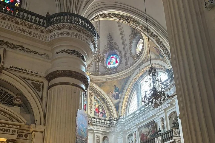 Ornate interior of a cathedral featuring a painted dome and stained glass
